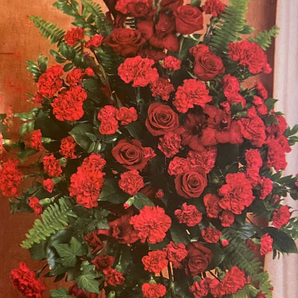 Tall standing spray of red roses and carnations with greenery