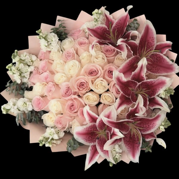 Pink and cream roses with large pink lilies in a wrapped bouquet