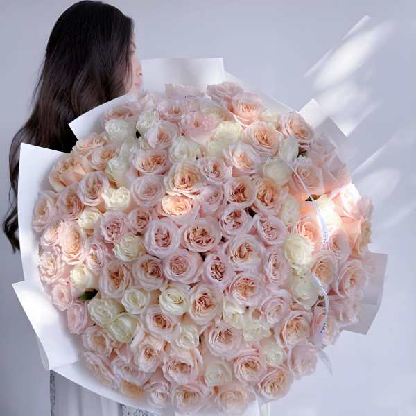 Large bouquet of pale pink and cream roses wrapped in white paper