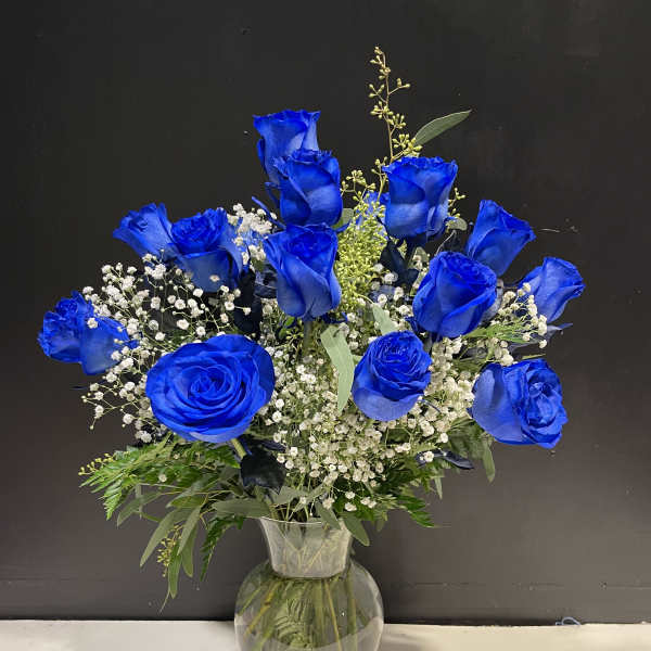 Blue roses in a clear glass vase with baby's breath
