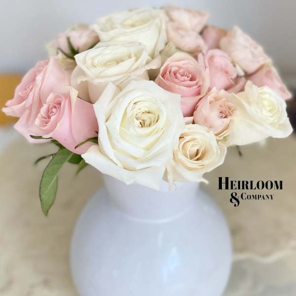 Pink and white roses arranged in a white vase