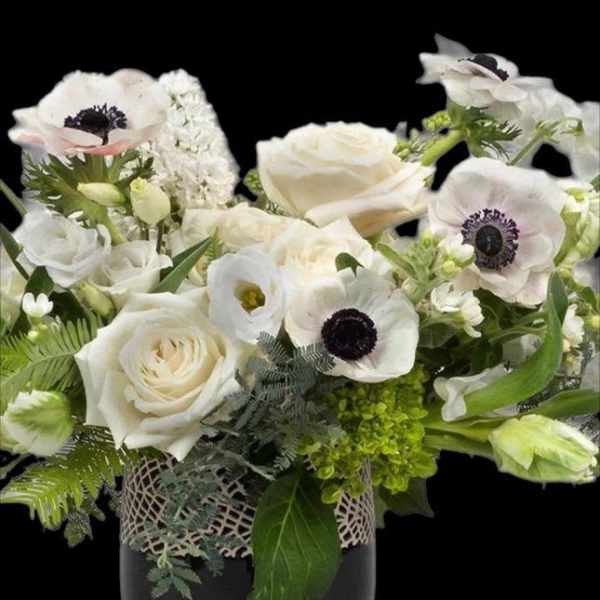 White roses and anemones arranged in a dark vase