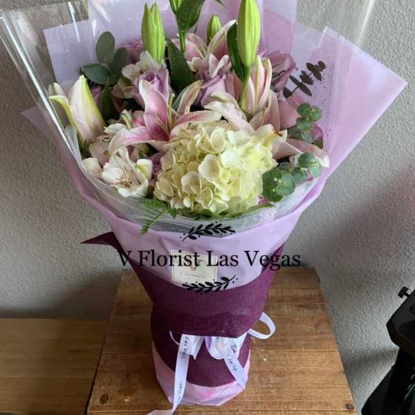 Bouquet of pink lilies and pale hydrangea wrapped in lavender paper