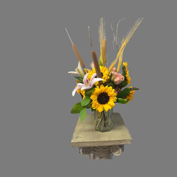Sunflowers and lilies arranged in a clear glass vase