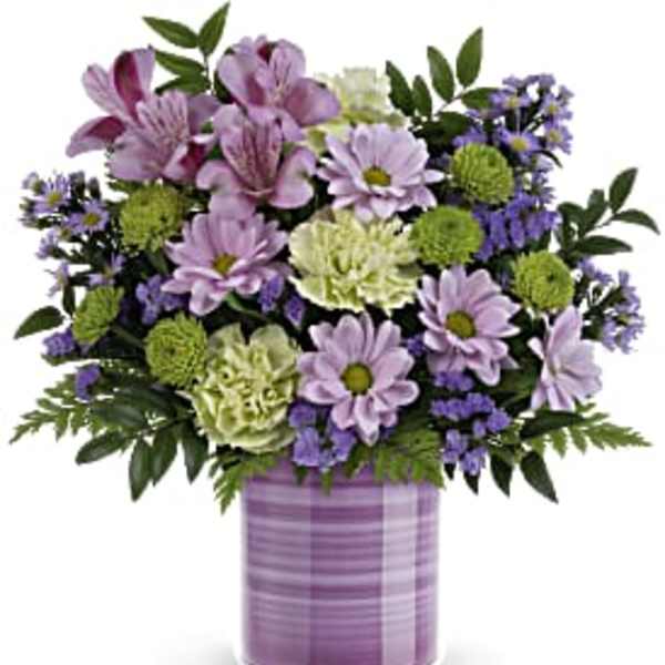 Lavender daisies, green mums, and pale carnations in a striped lavender ceramic cylinder vase