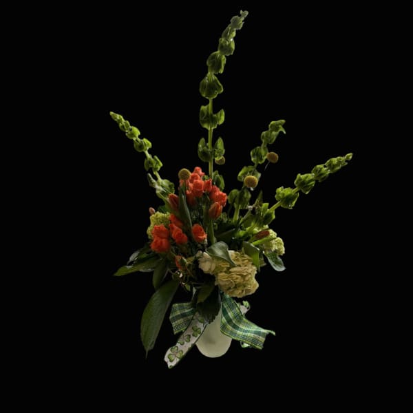 Tall floral arrangement with orange blooms and green spikes in a white vase