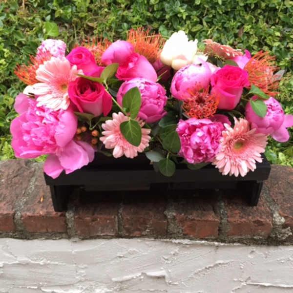 Pink floral arrangement in a black rectangular container