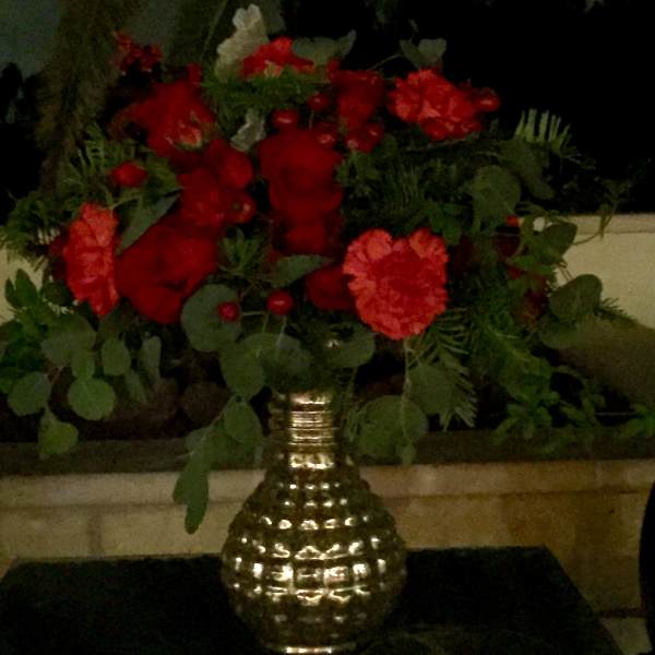 Red carnations in a gold vase with greenery