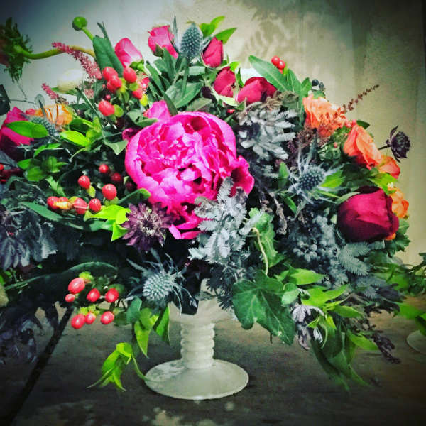 Bright mixed bouquet in a white pedestal vase with pink and orange blooms
