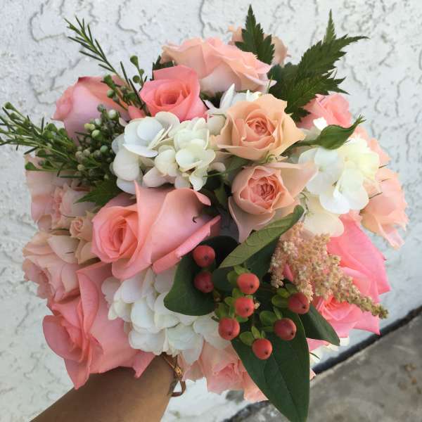 Handheld bouquet of pink and peach roses with white hydrangeas