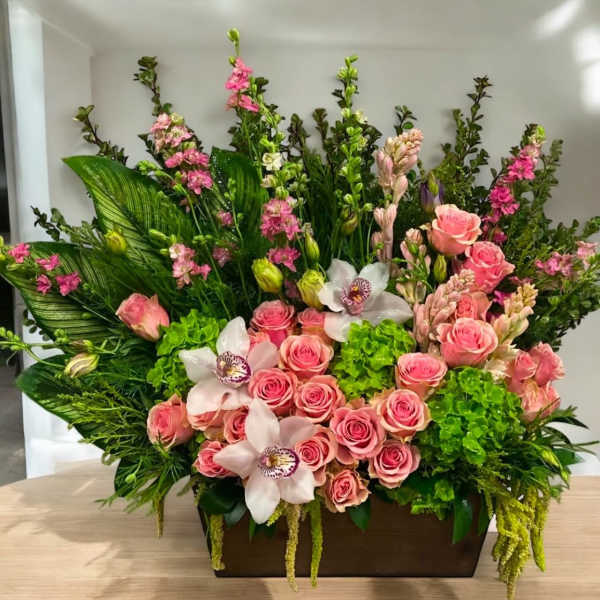 Large floral arrangement with pink roses, white orchids, and green blooms in a rectangular container