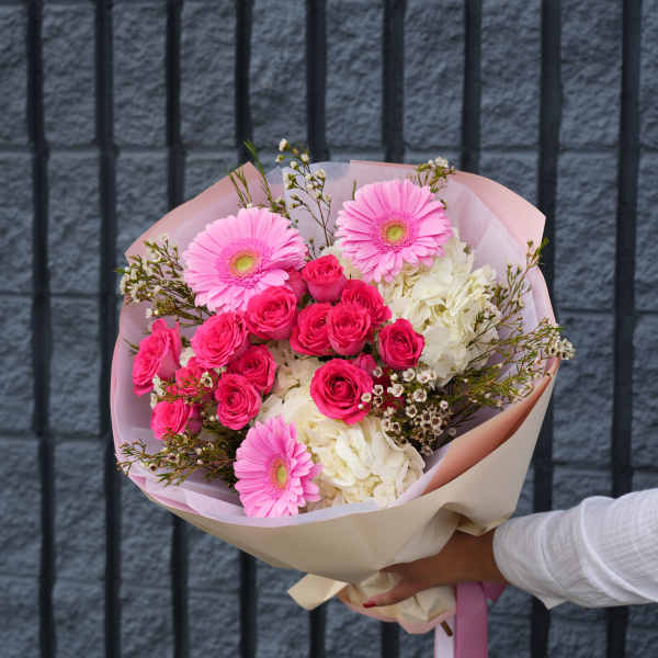 Pink gerbera and rose bouquet with white hydrangea in pastel wrap