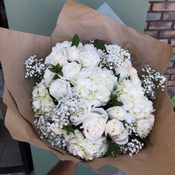 White rose and hydrangea bouquet wrapped in brown paper