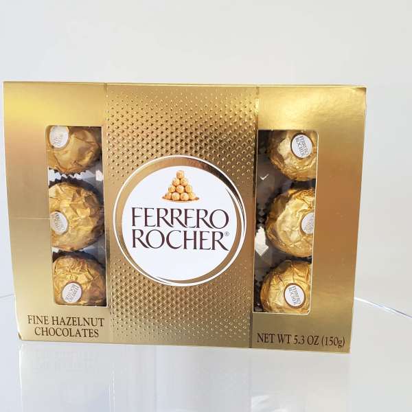 Gold box of Ferrero Rocher hazelnut chocolates on a clear surface