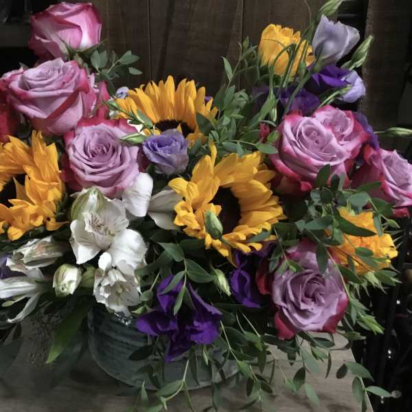 Bouquet of pink roses, sunflowers, and white flowers in a vase