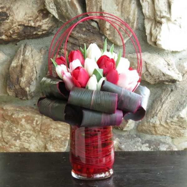 Bouquet of red and white tulips in a red glass vase