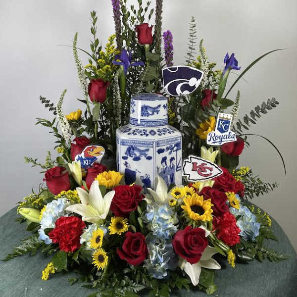Large floral arrangement with roses, lilies, and sunflowers around a blue-and-white vase