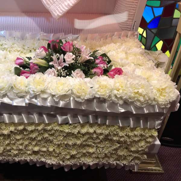 Large white floral casket spray with pink roses and lilies