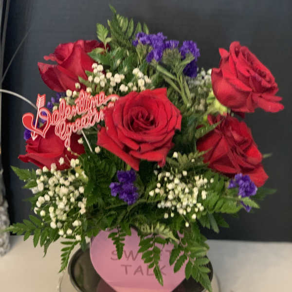 Red roses with purple filler flowers in a pink vase