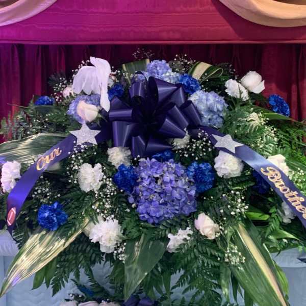 Large blue and white funeral spray with ribbons and a bow
