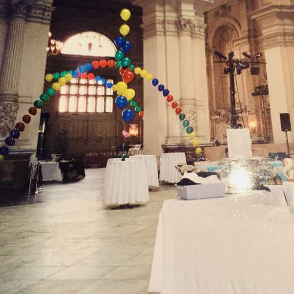 Colorful balloon arches in a large hall with tables below