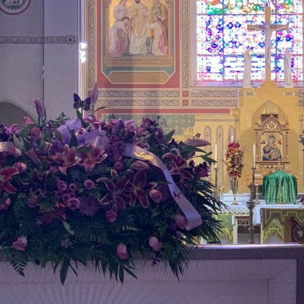 Large purple floral arrangement with ribbon in a church