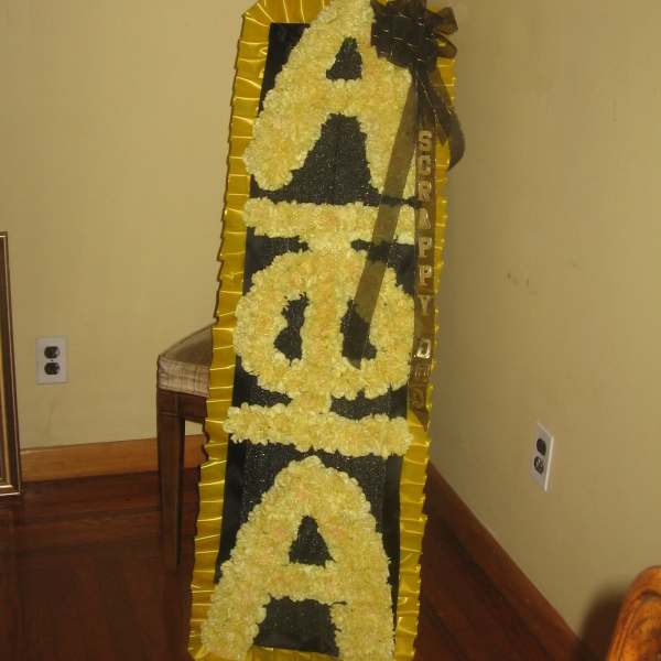 Tall floral standing tribute with yellow flowers spelling "SORRY"