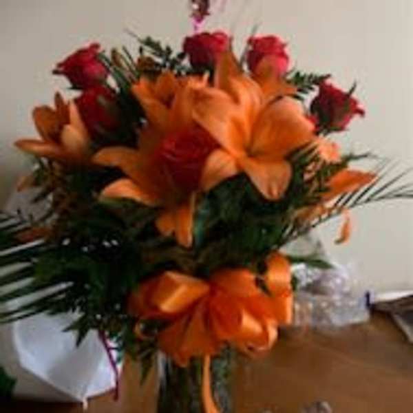 Bouquet of orange lilies and red roses with a heart-shaped balloon above