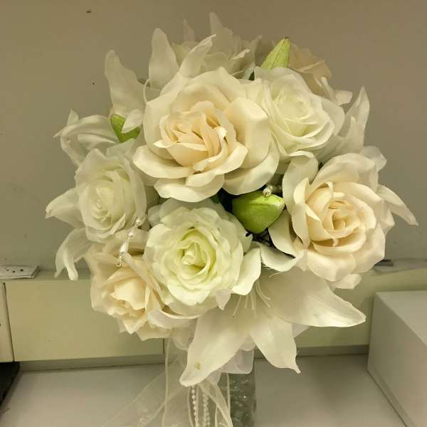 Cream rose bouquet with white lilies in a glass vase