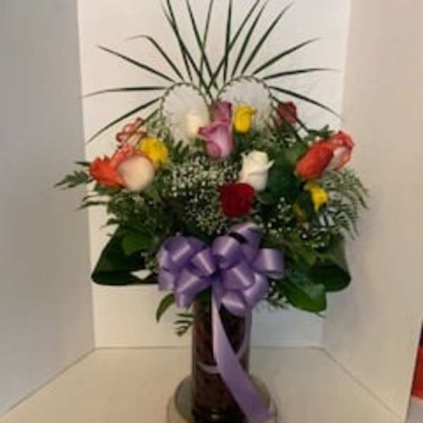 Mixed bouquet of roses with a purple ribbon in a vase