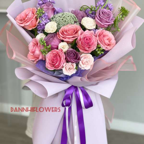 Hand-tied bouquet of pink and purple roses wrapped in lavender paper
