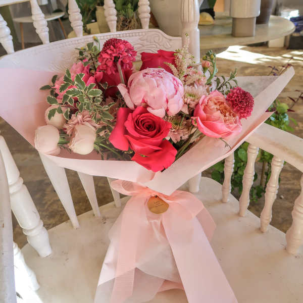 Pink and red rose bouquet wrapped in pale pink paper with a ribbon