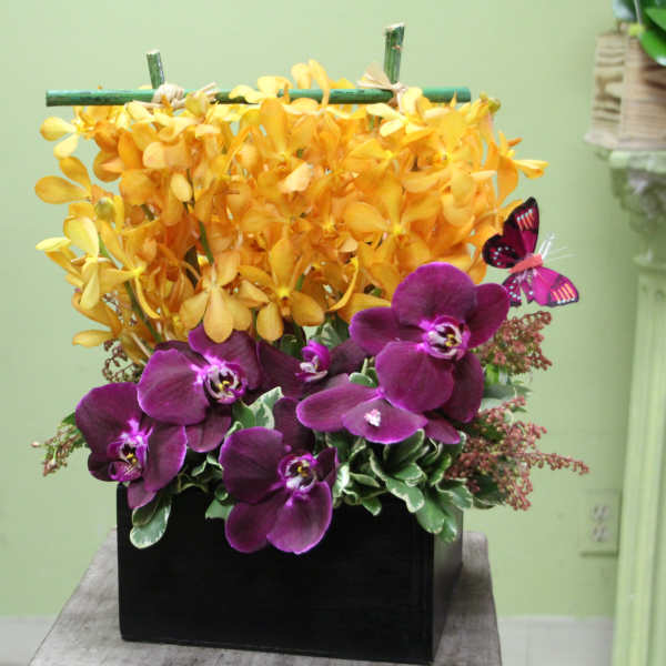 Purple orchids and yellow flowers in a black rectangular container