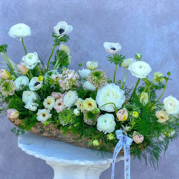 Large white floral arrangement in a rustic bark container