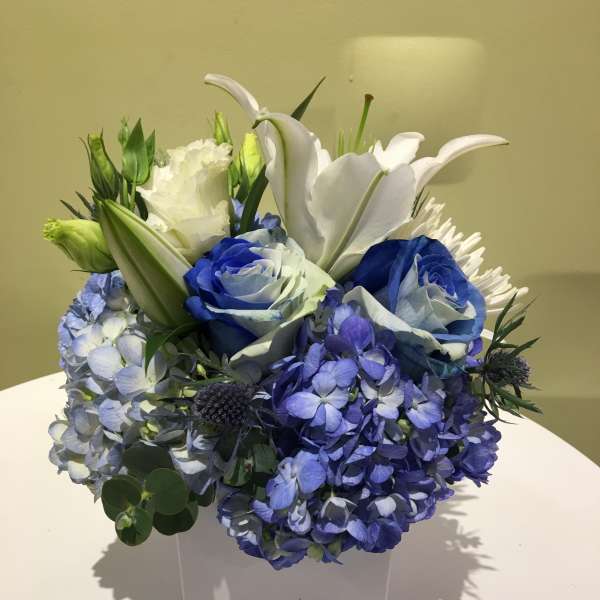 Blue and white floral arrangement in a white square vase