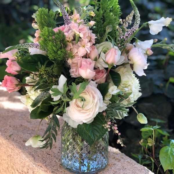 Pink and white floral arrangement in a textured glass vase