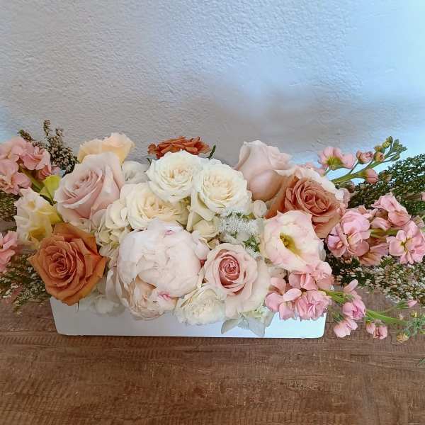 Low floral arrangement of pink and white roses in a white container