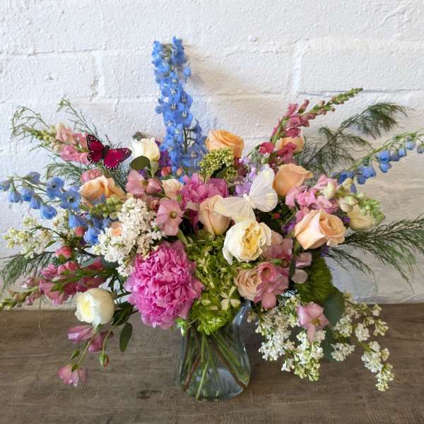 Mixed bouquet in a glass vase with pink, peach, white, and blue flowers