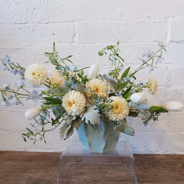 Cream flowers and pale blue blooms in a light blue vase
