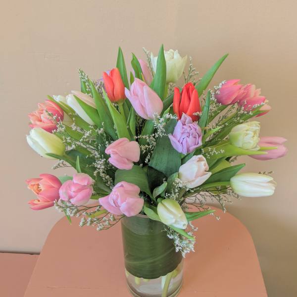 Mixed tulips in pink, white, and coral arranged in a glass vase