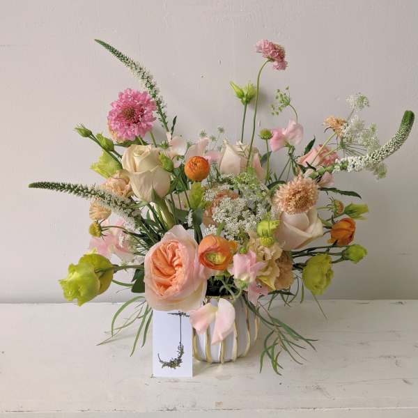 Mixed bouquet of pink, peach, white, and green flowers in a vase