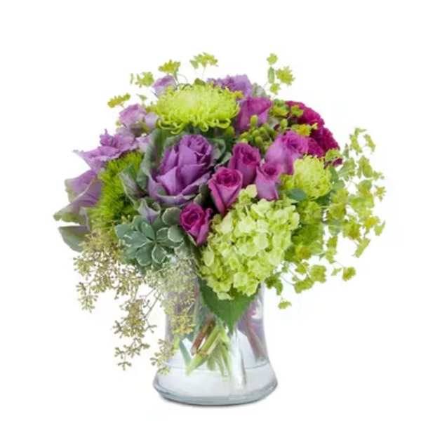 Purple and green bouquet in a clear glass vase