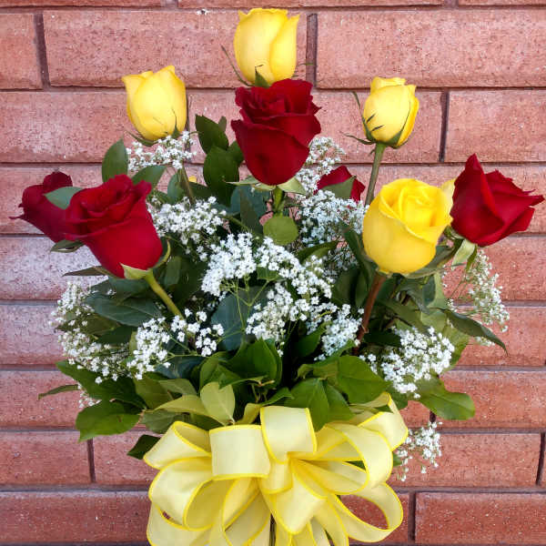 Bouquet of red and yellow roses in a glass vase with a yellow ribbon