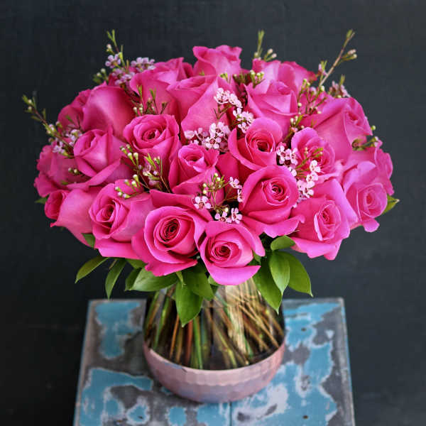 Pink roses arranged in a glass vase with small filler flowers