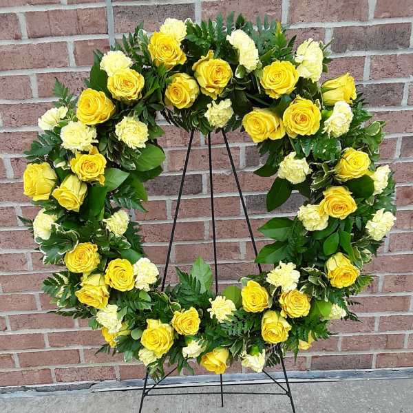 Yellow rose and white carnation wreath on a black stand