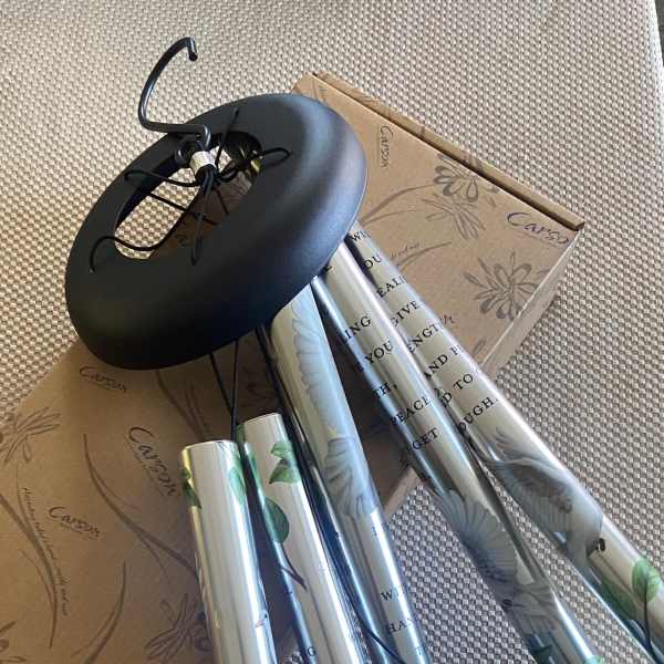 Silver wind chimes with black hanging parts and a cardboard box