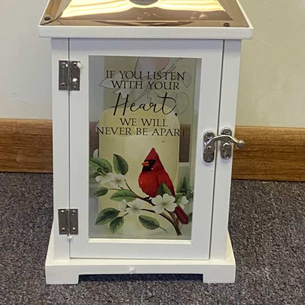 White lantern with a cardinal and floral print on the door