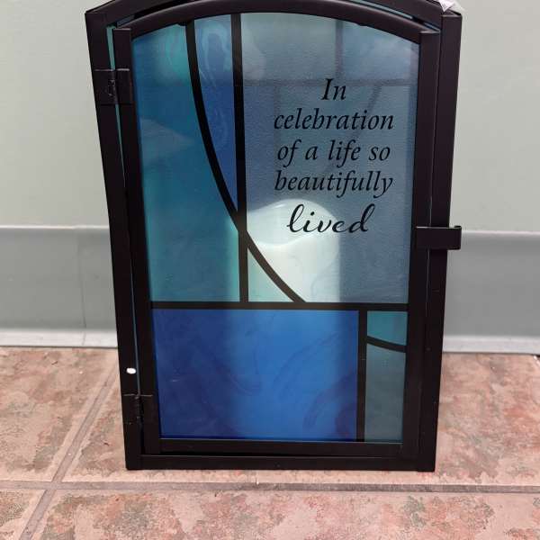 Decorative memorial lantern with blue glass panels and a sympathy message