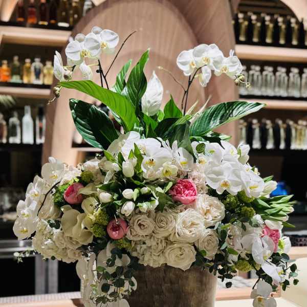 Large white orchid and rose arrangement in a pedestal container