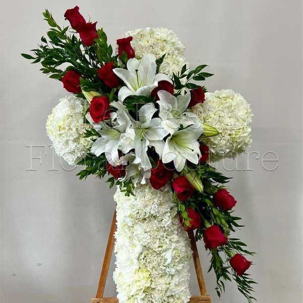 Cross-shaped floral arrangement with white lilies, red roses, and white hydrangeas